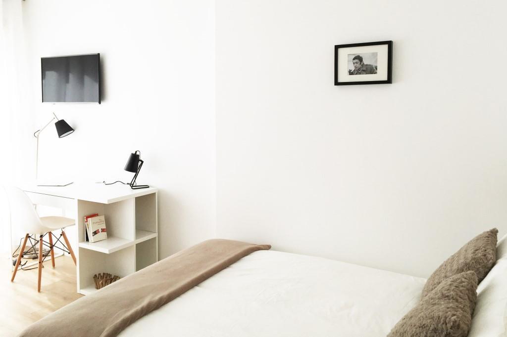 grand lit dans un studio meublé moderne